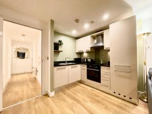 a kitchen with white cabinets and black appliances at Chic Leeds City Apartment, Free Parking, Balcony in Leeds +8 photos