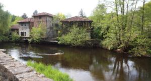 un fiume con due edifici antichi accanto a un fiume di Chambres d'hôtes Le Veilleur de Noblat a Saint-Léonard-de-Noblat