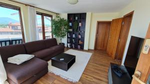 a living room with a brown couch and a tv at Magic Sea View in Tsarevo