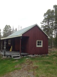 un fienile rosso con un portico in un campo di Båtstø Camping a Elga