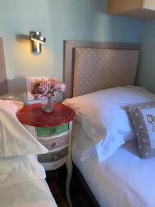 a table with a vase of flowers on a bed at Serendipity in Sutton on the Forest
