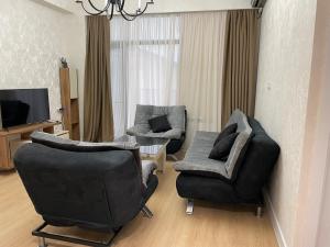 uma sala de estar com duas cadeiras e uma televisão em Apartment D. Digomi em Tbilisi