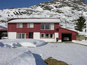 una casa rossa di fronte a una montagna innevata di Nydelig leilighet i første etage. a Sund