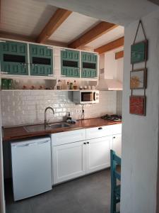 a kitchen with white cabinets and a sink at CASA DEL MAQUINISTA in Aguatona