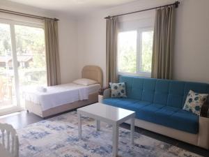 a living room with a blue couch and a bed at Olympos Apart in Olympos