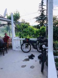 a man sitting on a porch with his bike and shoes at Flora's Guesthouse 'The Fir Gate' in Gjirokast&euml;r