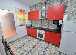 Il comprend une cuisine équipée de placards rouges et d'un réfrigérateur blanc. dans l'établissement Apartamento Camino Al Castillo, à Xàtiva