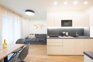 a kitchen and living room with a table and a couch at Meranosuites - Therme in Merano
