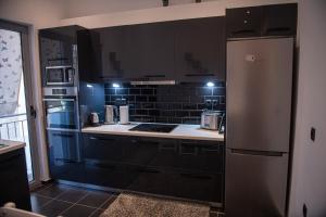 a kitchen with black cabinets and a refrigerator at Sophia’s place in Piraeus