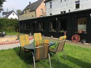 einen Tisch und Stühle in einem Hof mit einem Gebäude in der Unterkunft Gästehaus Bendsieferhof in Monschau