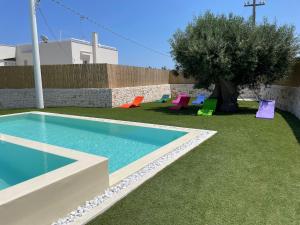 a pool with chairs and a tree in a yard at Tuo Hotel in Polignano a Mare