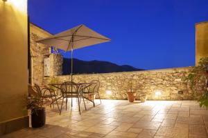 a table and chairs with an umbrella on a patio at Papiriana la casa del borgo_ breathtaking sea wiew in Fosdinovo