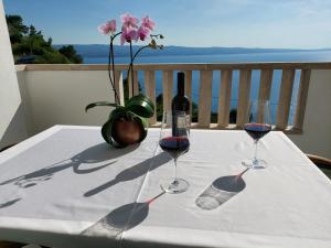a table with two glasses of wine and a vase with flowers at Apartmani Cvita in Omiš
