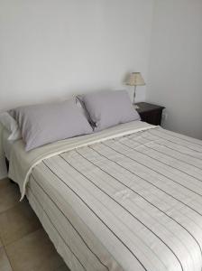 ein Schlafzimmer mit einem Bett mit einer weißen Tagesdecke in der Unterkunft Departamentos Defensa Sur in Concepción del Uruguay