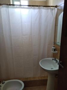 ein Badezimmer mit einem Waschbecken und einem weißen Duschvorhang in der Unterkunft Departamentos Defensa Sur in Concepción del Uruguay