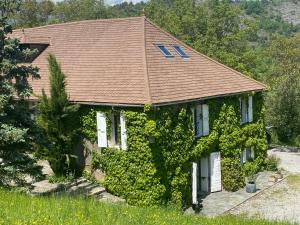 une maison recouverte de lierre avec un toit brun dans l'établissement La Genevraie, à Gap