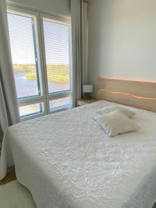 a bedroom with a white bed with two windows at River 29, Baritoni in Pori