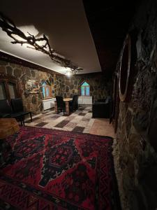Qusar Forest في كوسار: غرفة معيشة مع سجادة حمراء وجدار حجري