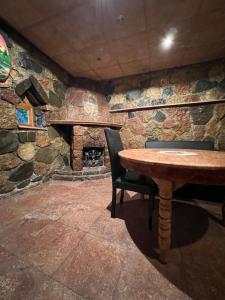 Qusar Forest في كوسار: غرفة حجرية مع طاولة وكراسي ومدفأة