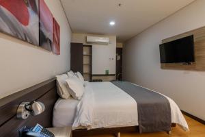 a bedroom with a bed and a flat screen tv at Hotel Vivre in Medellín