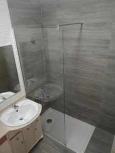 uma casa de banho com um lavatório e uma cabina de duche em vidro. em Marina Apartment em Portimão