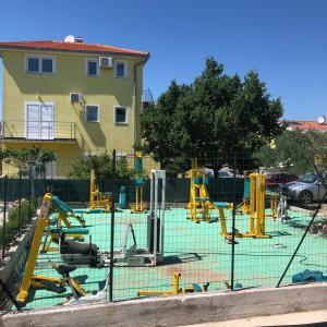 a playground with yellow equipment in front of a building at Lipovac resort Ficus in Bilice
