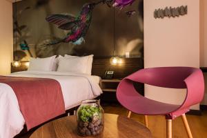 a hotel room with a bed and a pink chair at Hotel Vivre in Medellín