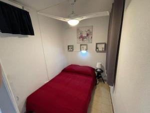 - une petite chambre avec un lit rouge dans l'angle dans l'établissement L'escale, à Carqueiranne