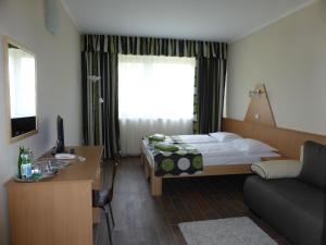 a hotel room with a bed and a desk with a computer at Sástó Hotel in Matrafured