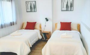 two beds in a room with white and red pillows at Agradable casa con terraza en S'Agaró in Sant Feliu de Guixols