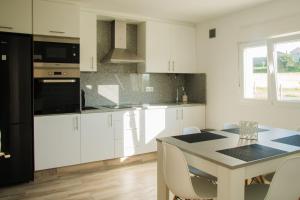 a kitchen with white cabinets and a table with chairs at Casa O Souto in Mazaricos