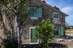a stone house with green shutters and a tree at Istrian green house in Portorož