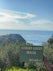 a person holding up a sign that reads ishtar greek house at Istrian green house in Portorož