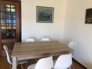 Piso centro de Raxò في راكسو: غرفة طعام مع طاولة خشبية وكراسي بيضاء