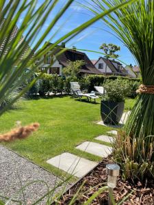 コンスタンツにあるTolle Ferienwohnung Le Gira mit eigenem Gartenのヤシの木が植わる芝生と椅子のある庭園