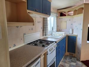 a kitchen with blue cabinets and a stove top oven at 6 Berth Seaview Ingoldmells Park Lodge in Ingoldmells