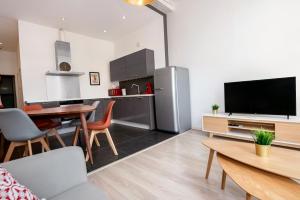 uma cozinha e sala de estar com televisão e mesa em Les Cerisiers - Appart de Standing à Namur Centre em Namur