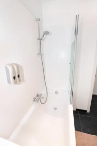 y baño blanco con ducha y lavamanos. en Les Cerisiers - Appart de Standing à Namur Centre, en Namur
