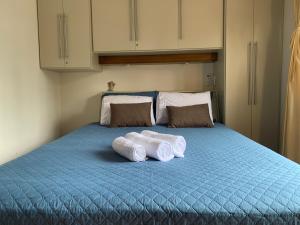 two rolls of towels sitting on a blue bed at Apto próximo aos pontos turísticos e restaurantes in Gramado