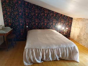a bedroom with a bed with a floral wallpaper at L'Appartement de la MAISON BLEUE in Villeréal +4 photos