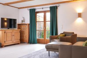 a living room with a couch and a tv at Alpinlife Chalet in Bad Kohlgrub