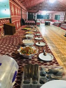 una mesa larga con platos de comida. en Red Mountain Camp, en Wadi Rum