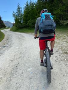 un hombre con una mochila montando una bicicleta por un camino de tierra en Maison Perriere - Chambres d'hôtes & Jacuzzi, en Saint Vincent