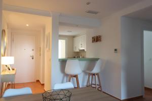 ein Wohnzimmer mit weißen Stühlen und eine Küche in der Unterkunft Blue Oliva Nova MET & Golf in Oliva + 29 Fotos