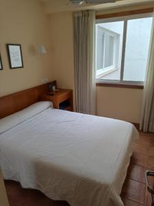 um quarto com uma cama branca e uma janela em Hotel Marycielo em Sanxenxo