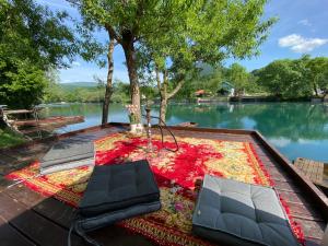 a table with two chairs and a rug next to a lake at River Luxury House in Bihać