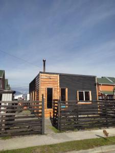 a small wooden house behind a wooden fence at Cabaña marteo in Chaitén