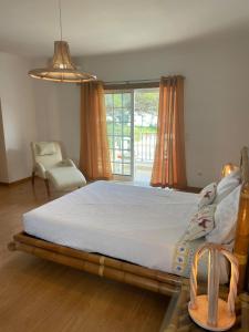 a bedroom with a bed and a chair and a window at Villa 3 Irmãos in Alvor
