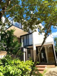 普拉亚卡门GLASS JUNGLE VILLA with amazing green views -10 min DT的白色的房子,有黑窗和树