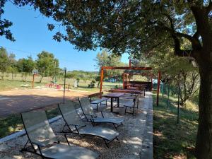 einen Picknicktisch und Stühle unter einem Baum in einem Park in der Unterkunft Grand Veles camp in Pula